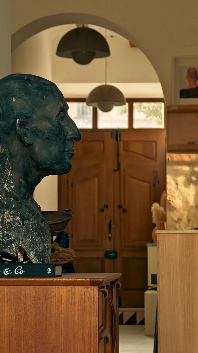Bronze bust in profile before an arched doorway in warm light
